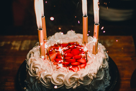 Closeup of candles on birthday cake with white icing.