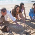 Free A Family Covering a Boy with Sand on the Seashore Stock Photo