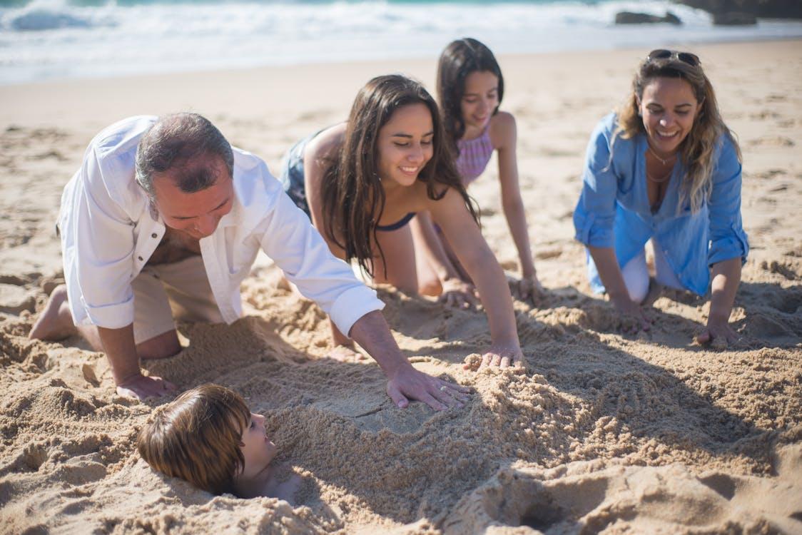 Free A Family Covering a Boy with Sand on the Seashore Stock Photo