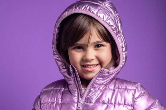 A young child wearing a purple coatAI-generated content may be incorrect.