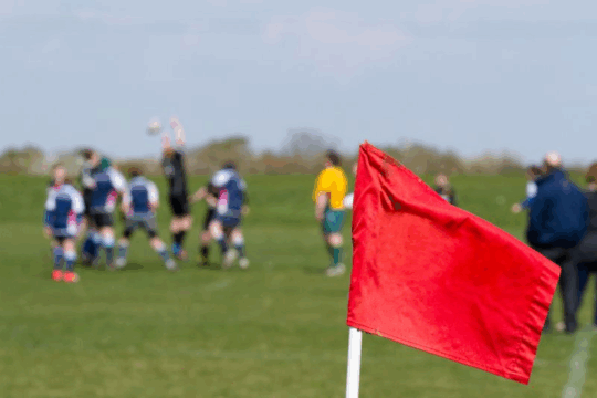 Red corner flag on sports field.